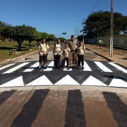 Policial militar com alunos sobre uma faixa de pedestre elevada: mais seguranÃ§a prÃ³ximo das escolas